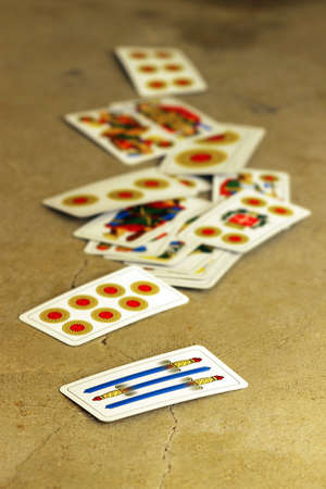 Several old Italian playing cards with shallow depth of field on old stone surfaceの写真素材