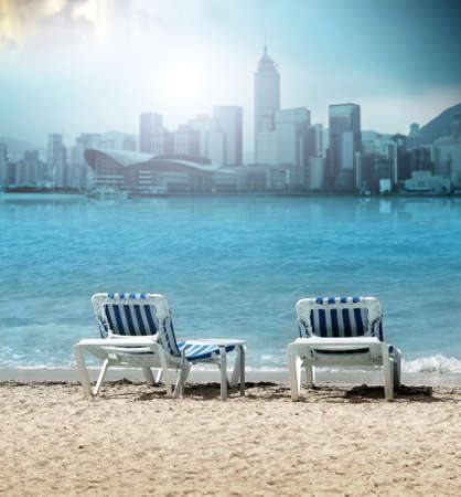 Beach chair on sand with ocean and modern city viewの写真素材