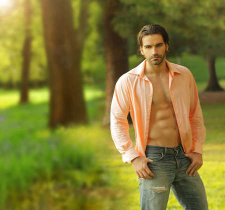Beautiful male model with open shirt in outdoor settingの写真素材