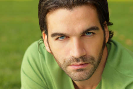 Close up portrait of a good looking male model in green sweater against natural green backgroundの写真素材