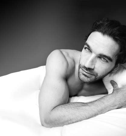 Sexy black and white portrait of a good looking guy in bedの写真素材
