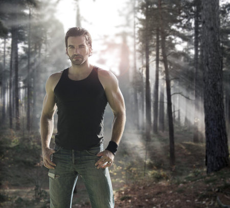Portrait of a good looking male model in dramatic forest with rays of light behind