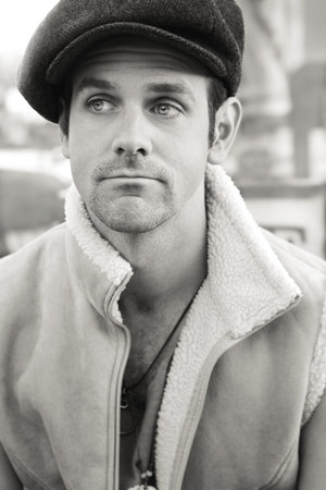 Portrait of a young man outdoors in sepia tones wearing hat and vest