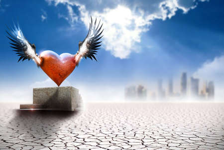 Conceptual fine art work depicting a winged heart on a pedastal in barren landscape with city in far backgroundの写真素材