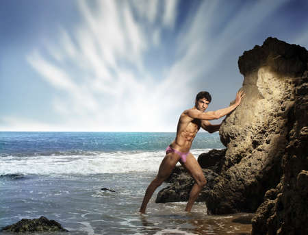 Sexy portrait of a hot buff male fitness model  on the beach with dramatic ocean and sky の写真素材