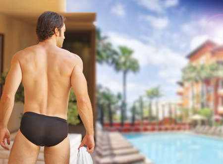Beautiful sexy man with nice body from behind at glamorous resort swimming pool の写真素材