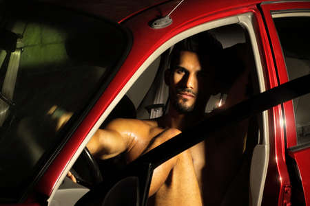 Portrait of a sexy young man sitting in car の写真素材