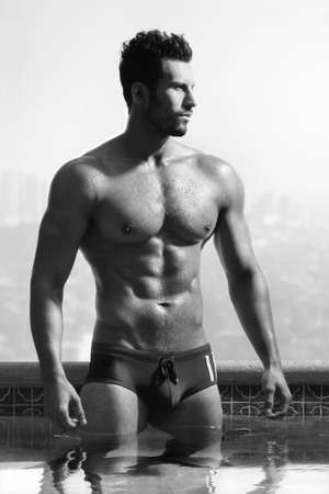 Classic fashion portrait of a young healthy good looking macho man model athlete at swimming poolの写真素材