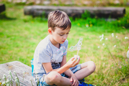 Boy sitting on a bench with soap bubblesの写真素材