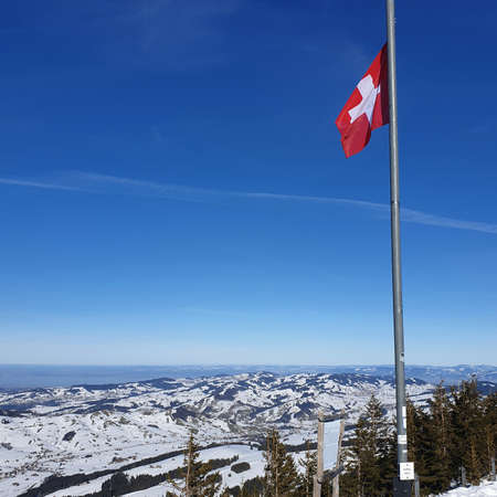 Waving Swiss Flag with Snowy Mountains in Background, Switzerlandのeditorial素材