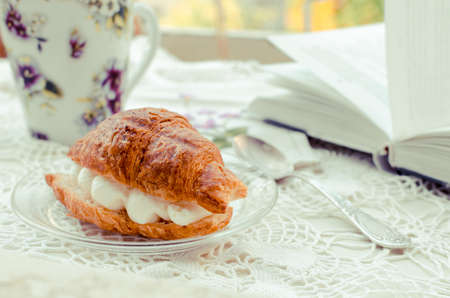 Coffee and croissant with whipped cream, violet ornamentの写真素材
