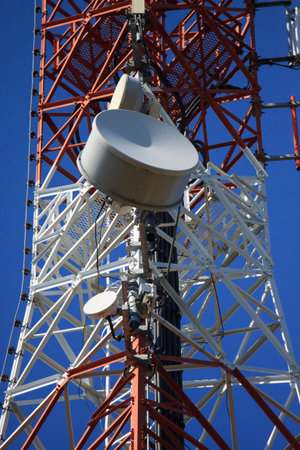 Telecommunication mast with microwave link and TV transmitter antennas over a blue sky 