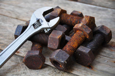 Old bolts with adjustable wrench tools on wooden background.の写真素材