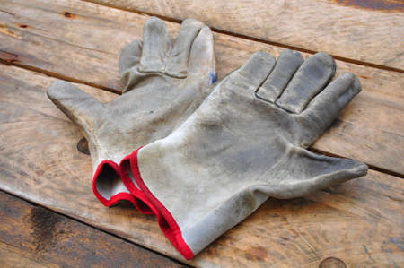 Old safety gloves on wooden background, Gloves on dirty works.の写真素材
