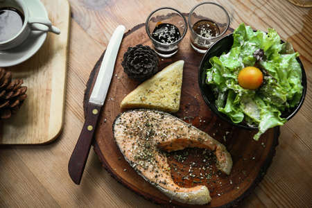 Salmon steak on wooden table in restaurantの写真素材