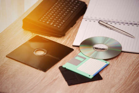 desk with note ,floppy disk A, floppy disk B and memory drive in home office, private office and modern desk in modern life, online market and planning for work, document and paper on desk.の写真素材