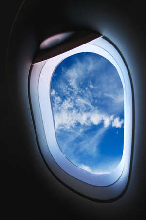 Plane window with cloudy blue skyの写真素材