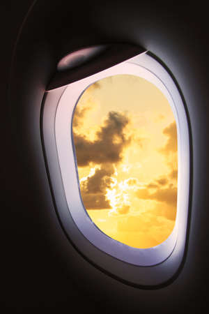 Plane window with sunset cloudy sky from the windowの写真素材