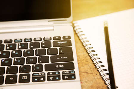 Laptop with notepad on wooden tableの写真素材