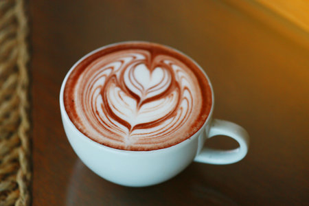 Barista hands pouring warm milk in coffee cup for making latte art. Multi skill of barista to make coffee drink in coffee shop with warm lightの写真素材
