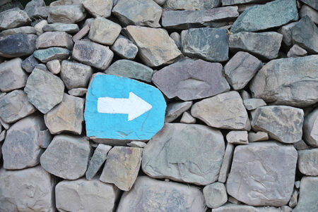 Painted signal pointing arrow over a rock wallの写真素材