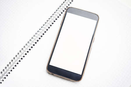 Modern smartphone mock up with white blank screen on notebookの写真素材