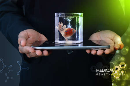 Man is holding a heart in glass of water  and tablet computerの写真素材