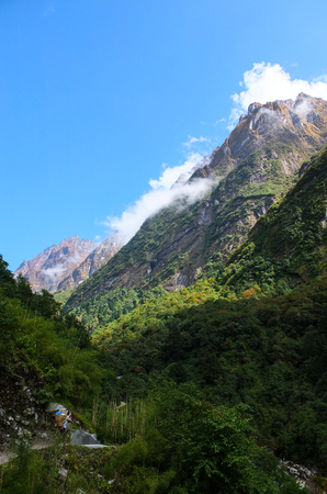 A porter carrying trekker's belongings and walking into a very beautiful valley in Nepalの写真素材