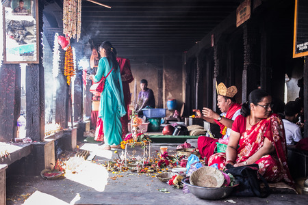 Nepal - 27 October 2014 : A guy praying in small ritual ceremony with couple of believers nearby, indoor. The image shows a normal sacred activity of local people in Nepal.のeditorial素材