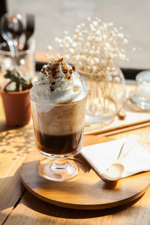 Capuchino coffee shop dessert recipe, whipping cream topping; lay on wooden plate and spoon. chilling on sunny day.の写真素材