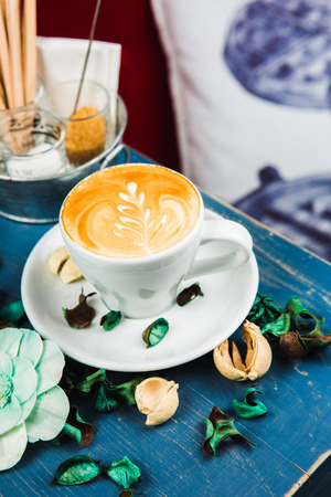 Coffee cup latte foam arts in heart shape with porps by stylist, lay on blue wood table.の写真素材