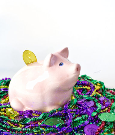 Mardi Gras piggy pank on a pile of Mardi Gras beads and coins