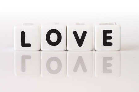The word love spelled in game dice reflected on isolated white background.の写真素材