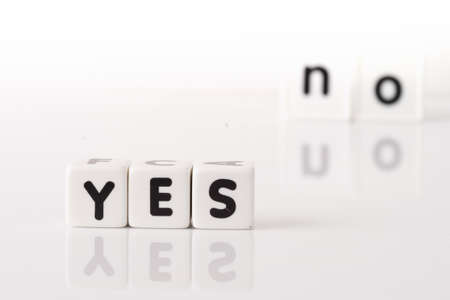 Yes spelled in dice letters in foreground with the word no out of focus in background  Isolated on white background の写真素材