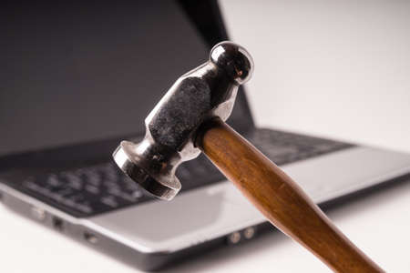 Hammer about to smash an out of focus laptop in backgroundの写真素材