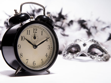 Time to celebrate. Alarm clock with Mardi Gras mask and feather boa