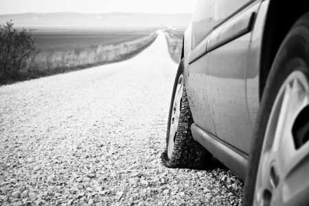 A flat tire with a view of a long dirt road into the distance