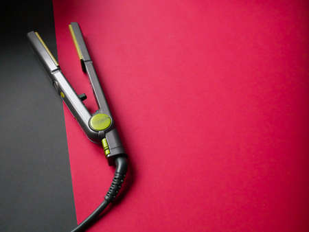 Electric curling iron with ceramic plates isolated on colored background.の写真素材