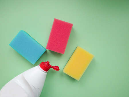 Set of housewives for washing dishes. Dishwasher. Bottle of washing utensils, sponges on light green color background. Top view.の写真素材