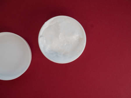 Natural cosmetic cream skincare product wellness and relaxation makeup mask on red background. Top view.の写真素材