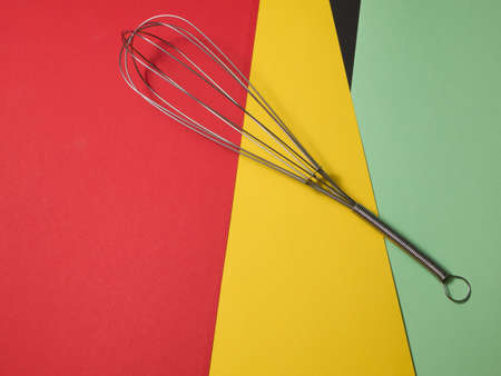 Stainless steel whisk isolated on colored background.の写真素材