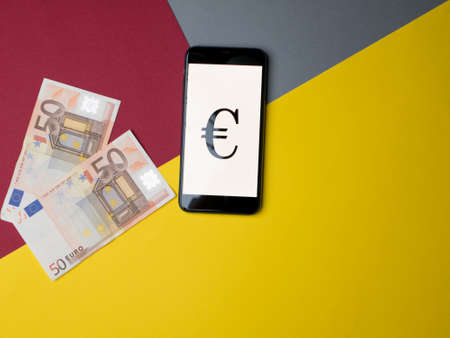 Madrid, Spain - May, 2020; Euro Iphone Application Screen with money on colored paper background. Copy space.のeditorial素材