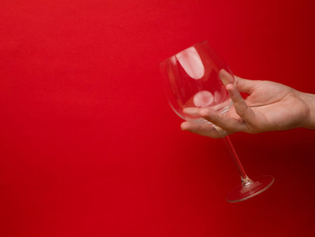 Hand holding an empty wine glass on background. Side view with space for copying. Concept of holiday backgrounds.の写真素材