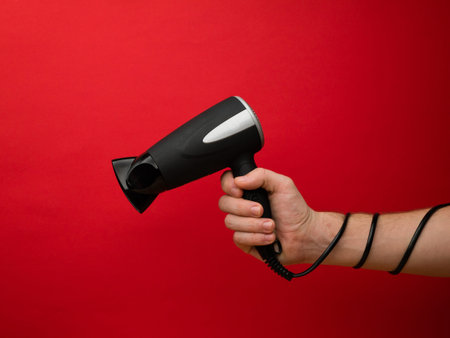 Male hand holding black hairdryer isolated on background. Hirdresser salon, barber shop, household...