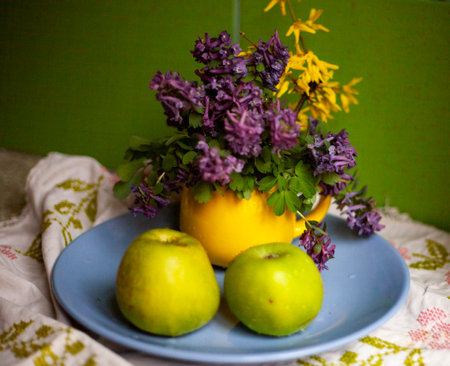 Still life of green apples andbouquet of purple spring flowersの写真素材