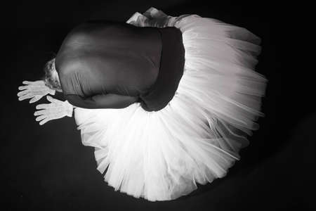 ballerina in a white lush dress sitting, arms outstretchedの写真素材