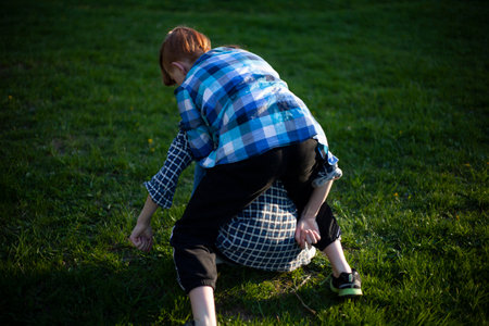 Boy and girl teenagers are fighting on the grass in natureの写真素材