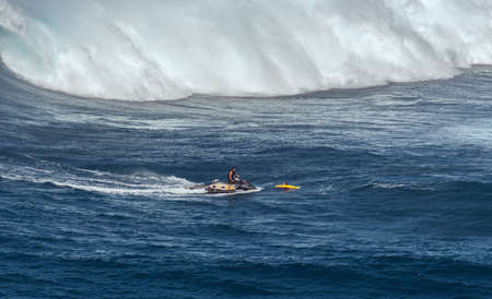 MAUI, HAWAII, USA - DECEMBER 15, 2013: jetski driver brings a surfer away from the next breaking waveのeditorial素材