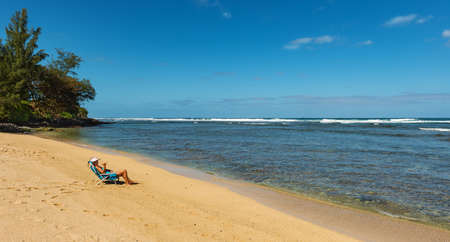 KAUAI, HAWAII, USA-DECEMBER 29, 2014: female tourist relaxing on a sandy beachのeditorial素材