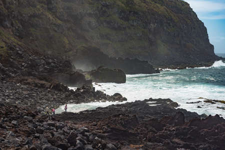 PONTA DEL GADA, SAN MIGUEL, AZORES-APRIL 26, 2016: tourists walking on a rough black rocky beachのeditorial素材